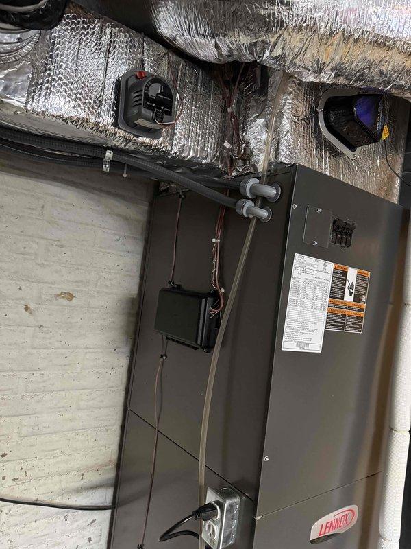 Replaced existing zoning system and installed new Lennox air handler unit in basement utility area. Configured extensive flexible ductwork network with reflective insulation to distribute conditioned air to multiple zones throughout the residence. Installed PVC condensate drain lines with shutoff valves, condensate pump with electrical connections, and refrigerant line set. Mounted control module and completed all electrical wiring including thermostat control cables and power supply connections to ensure proper zone control operation.