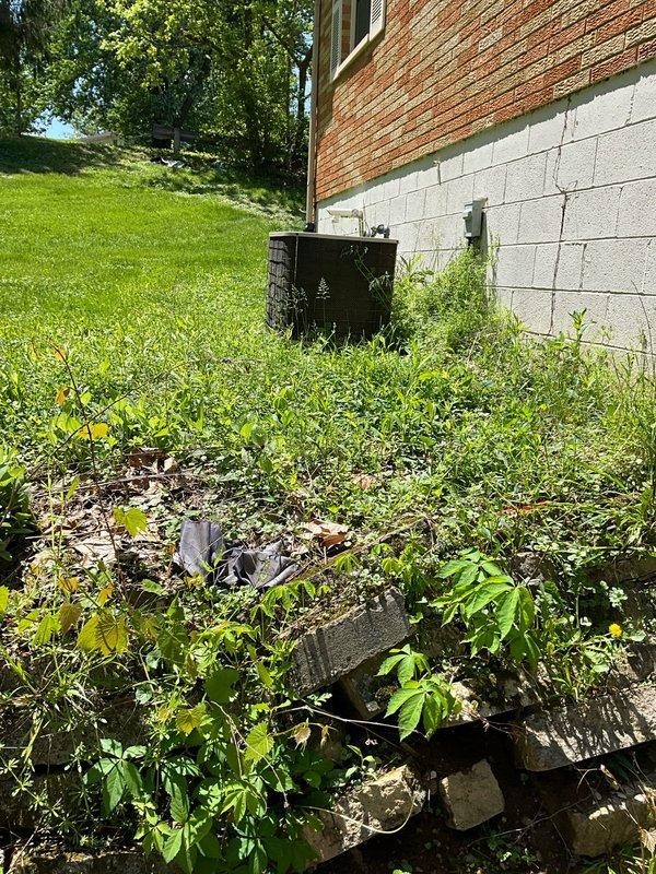 Conducted on-site evaluation of existing residential air conditioning system to provide replacement estimate. Inspected exterior condensing unit located at foundation level, assessed current equipment condition, installation accessibility, and surrounding site conditions including overgrown vegetation and debris near unit placement area. Documented existing system configuration, electrical service requirements, and refrigerant line routing for replacement specifications. Provided comprehensive replacement options and recommendations based on property requirements and current equipment setup.
