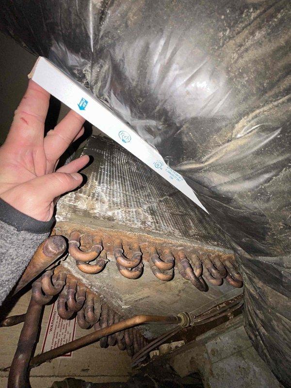 Responded to no cooling complaint and performed system diagnostic. Upon inspection, discovered evaporator coil assembly with severe corrosion and rust throughout the U-bend configuration, compromising heat transfer efficiency and likely causing refrigerant leaks. Documented heavily corroded coil condition and deteriorated ductwork showing moisture damage, dust accumulation, and possible microbial growth in attic-mounted air handler system, indicating extended exposure to condensate and humidity issues requiring immediate attention.