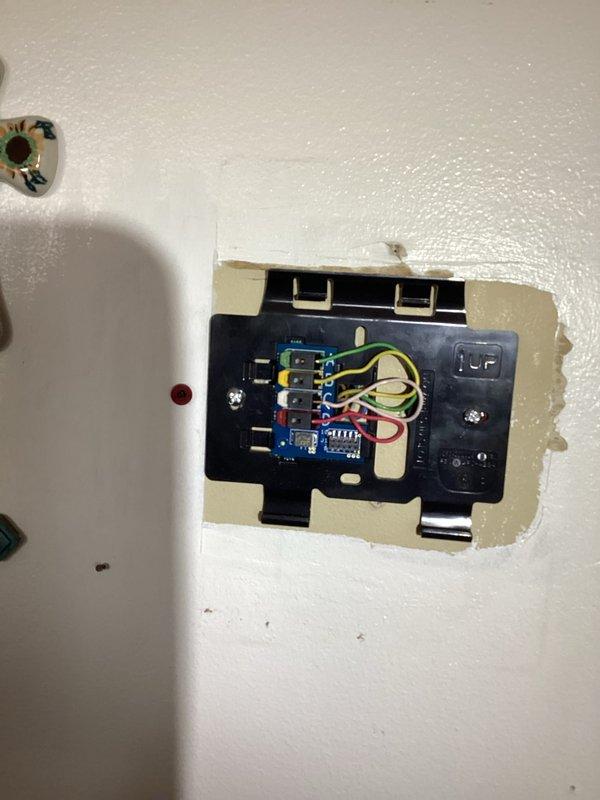 Returned to property with prepaid thermostat replacement unit and completed installation. Removed existing wall-mounted thermostat, disconnected all wiring from terminal block, and properly installed new control unit with all wire connections verified and secured to appropriate terminals including power, heating, cooling, and ground conductors. Tested system operation to confirm proper thermostat function and communication with HVAC equipment.