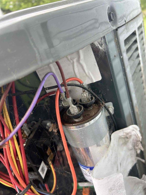 Responded to service call for outdoor condensing unit producing loud intermittent noise every two minutes. Inspected electrical components and capacitor connections, finding signs of age and environmental exposure on wiring and capacitor assembly. Verified thermostat operation and system cycling behavior, documented internal component condition with capacitor showing dirt accumulation and multiple wire connections intact.