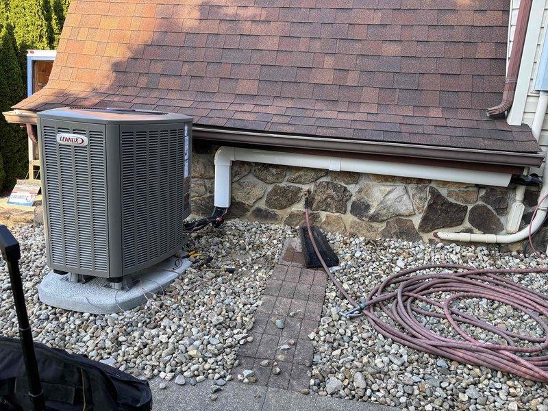 Completed full HVAC system installation featuring a Lennox heat pump and gas furnace at residential property. The outdoor heat pump unit was professionally mounted on a concrete pad with proper clearances, positioned against the stone foundation with adequate airflow access, and the indoor gas furnace component was integrated to provide dual heating capability for optimal year-round climate control and energy efficiency.