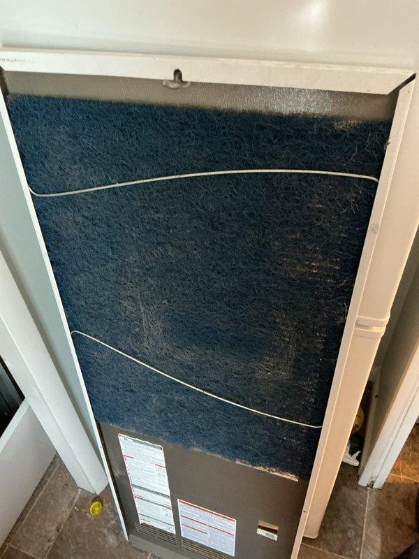 Completed basic monthly HVAC maintenance including cooling coil check and condenser coil check on residential air handler system. Observed heavily soiled air filter with significant dust and debris accumulation requiring replacement, though filter size specifications were not documented. Verified thermostat operation showing proper display function at 65°F setpoint with fan in auto mode.