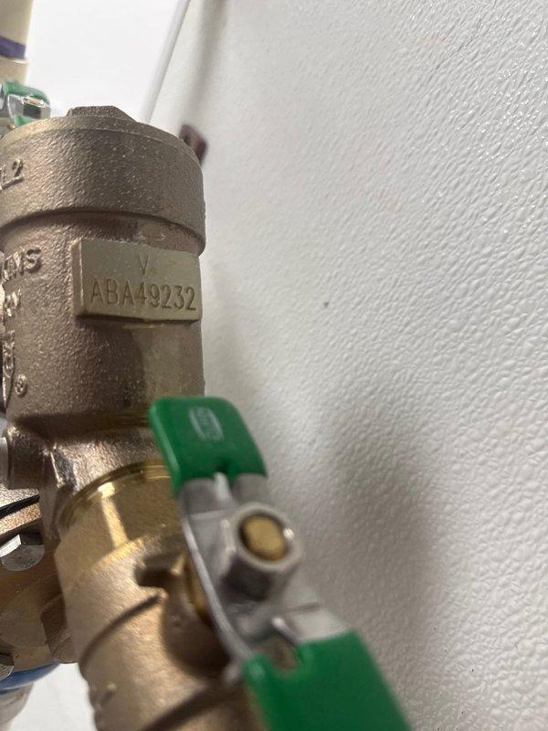 Inspected and serviced commercial backflow preventer assembly and associated isolation valves. The Watts brand backflow prevention device with test ports was examined for proper operation and compliance. Verified ball valve functionality with green handle actuator and confirmed all brass fittings and connections were secure. Documented equipment identification numbers and current system configuration for maintenance records.