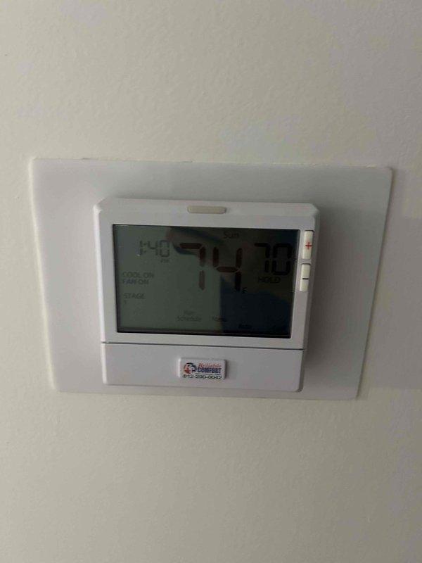 Responded to no cooling complaint on residential air conditioning system. Performed diagnostic inspection of indoor air handler unit and thermostat operation. Verified thermostat settings showing 74°F display reading and confirmed proper programming. Inspected air handler installation in utility closet, checking condensate drain lines, electrical connections, and unit accessibility for proper system operation.