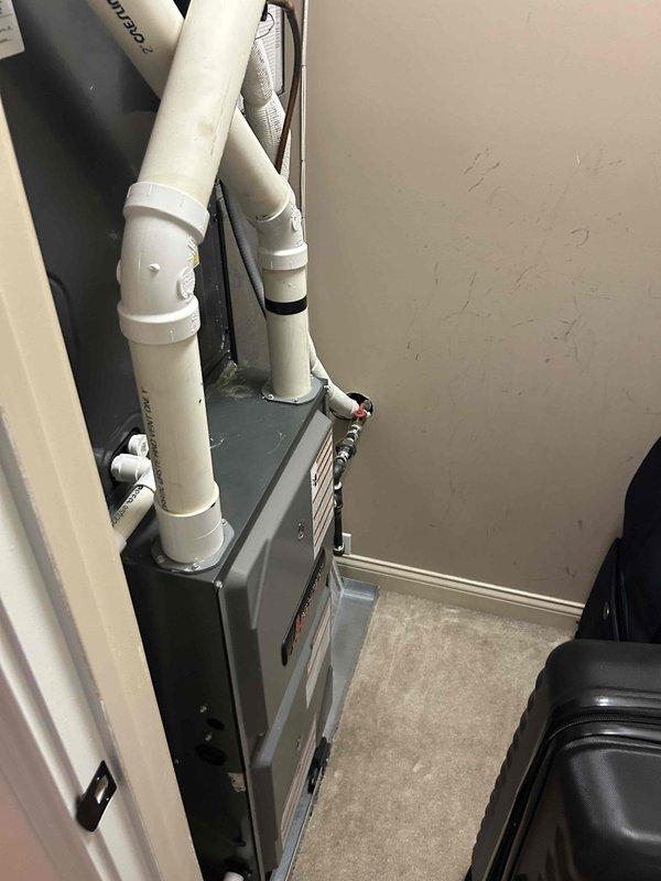 Responded to no cooling complaint on residential air conditioning system. Performed diagnostic inspection of indoor air handler unit and thermostat operation. Verified thermostat settings showing 74°F display reading and confirmed proper programming. Inspected air handler installation in utility closet, checking condensate drain lines, electrical connections, and unit accessibility for proper system operation.