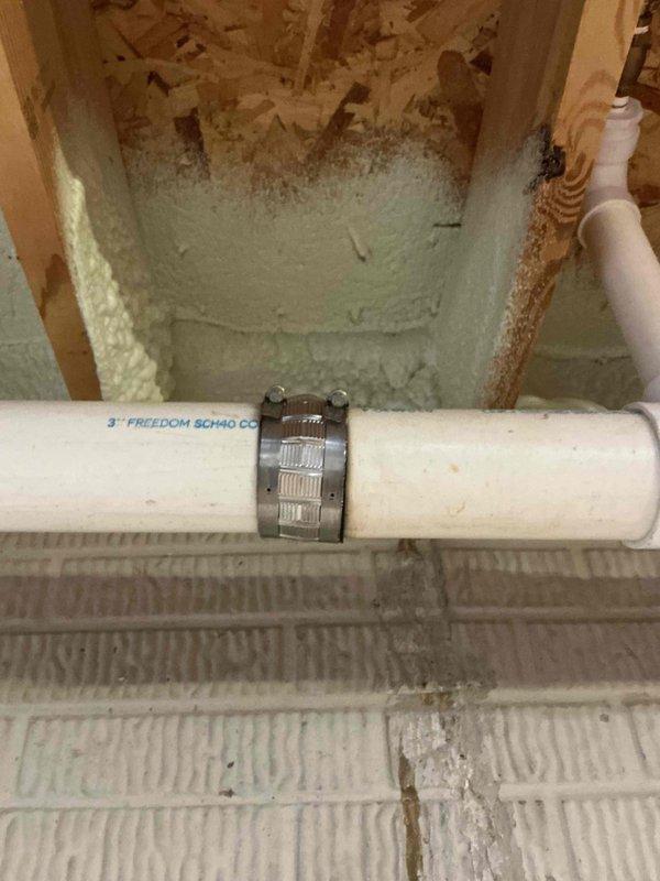 Installed missing Air Admittance Valve (AAV) under sink and replaced worn rubber boot on sewer pipe. Corrected improper gas line configuration where water heater gas supply was incorrectly tapped into furnace drip leg, creating an unsafe low point in the water heater supply line. Installed proper tee fitting to establish code-compliant gas line routing for both appliances. Secured 3-inch PVC drainage piping with metal hose clamps to ensure proper support and prevent future movement.