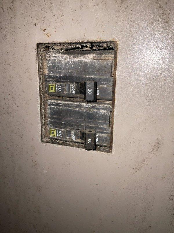 Conducted on-site assessment of non-operational HVAC system at rental property to provide replacement estimate. Inspected aging furnace unit from the 1980s-1990s located in basement utility area with exposed brick walls, noting significant dust accumulation, surface wear, and deterioration of surrounding components including corroded cylindrical equipment and discolored electrical panel with Square D breakers showing heavy grime buildup. Documented existing equipment condition and ductwork configuration through photographs for replacement system specifications.