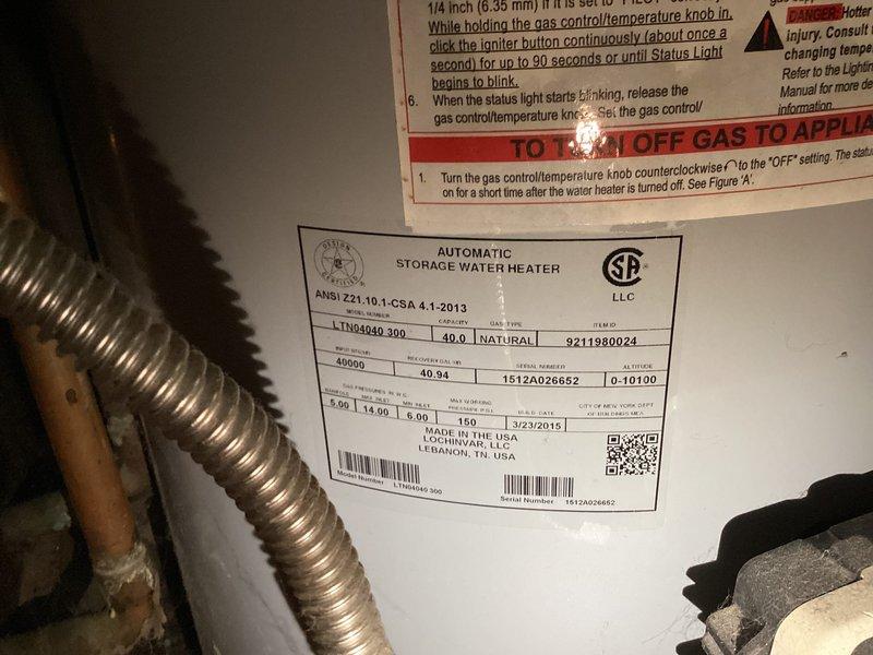 Responded to active water heater leak at residential property. Upon inspection, discovered a 2015 natural gas automatic storage water heater with severe corrosion and rust buildup at the top connections, particularly around the shutoff valve and copper pipe joints. The corrosion had compromised the integrity of the connections, resulting in active water leakage. Evidence of moisture damage was visible on surrounding wooden surfaces and extensive water staining on the wall, indicating prolonged exposure to leaking water. The metallic piping showed heavy condensation and deterioration. Documented the condition of the unit, including manufacturer specifications and serial number, along with the extent of corrosion damage for replacement recommendations.
