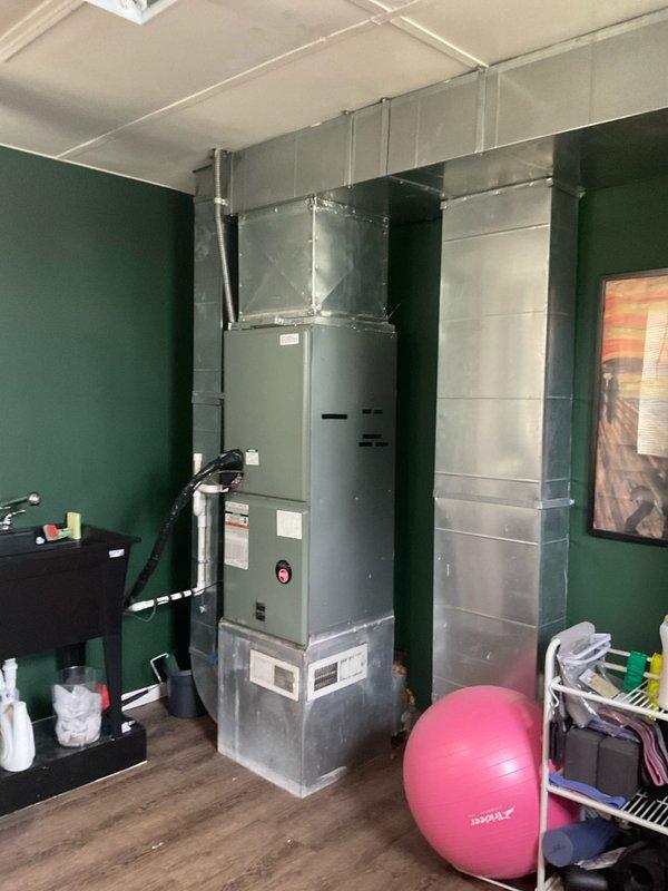 Conducted comprehensive site evaluation for full HVAC system replacement in basement utility area. Performed load calculation assessment on existing vertical air handler unit with multiple stacked components and ceiling-mounted ductwork distribution system. Documented current equipment configuration including gray metal air handler installation against interior wall with sheet metal supply ductwork connections. Inspected electrical service supplying HVAC system, noting dual 60-amp circuit breakers with visible dust accumulation requiring attention during replacement. Prepared complete system replacement estimate with expedited timeline for installation within one week per customer requirements.