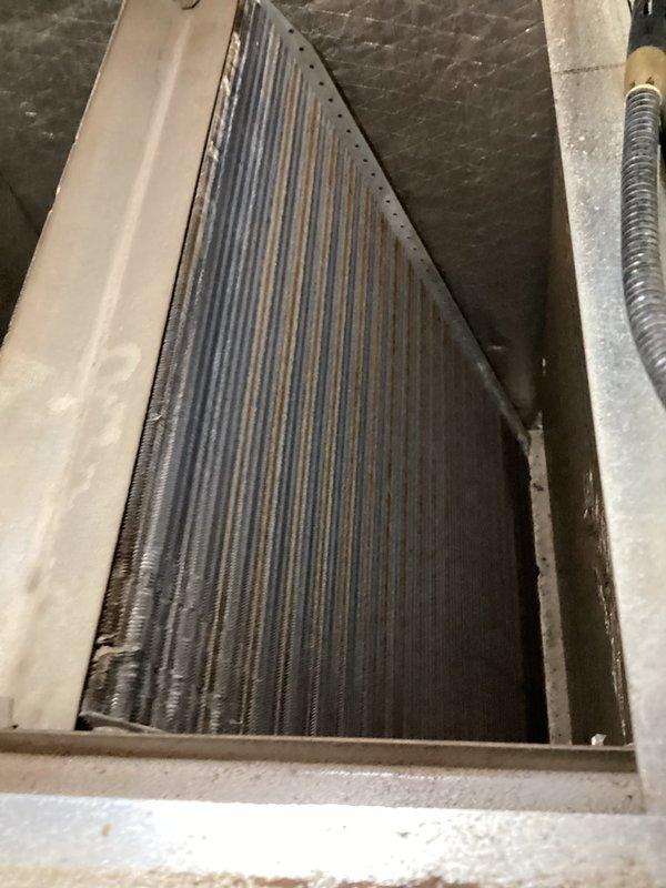Responded to service call for frozen refrigerant line and unusual system noises. Upon arrival, performed visual inspection of air conditioning system and identified severely restricted airflow due to heavily contaminated evaporator coil with significant dust accumulation and debris buildup on lower fins. Cleaned evaporator coil thoroughly to restore proper airflow, checked refrigerant charge and operating pressures, verified thermostat operation showing system set to cooling mode at 80°F setpoint with current temperature at 75°F. System returned to normal operation with no unusual noises and proper cooling cycle confirmed.