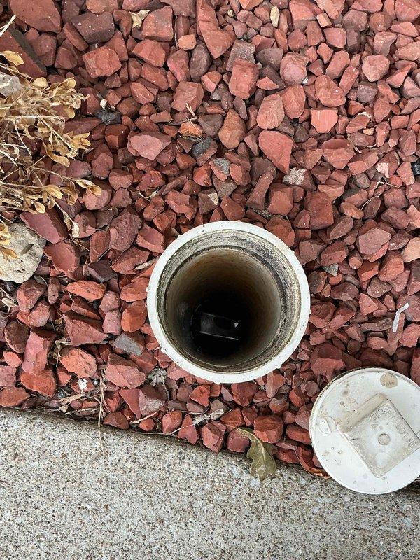 Responded to service call for multiple drains backing up into kitchen. Upon arrival, located and accessed exterior sewer cleanout at ground level near landscaping border. Removed heavily rusted cast iron sewer access cover, revealing chamber with accumulated debris, sediment, and organic matter buildup. Inspected secondary PVC cleanout access point in landscaped area, noting sediment accumulation on interior pipe walls. Performed mainline sewer clearing to address blockage causing backup in multiple interior drains. Verified proper drainage flow restored to all affected fixtures. Replaced cleanout covers and left access points secure.