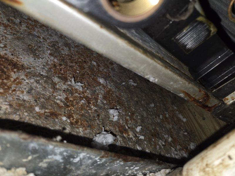 # HVAC Service - Water Leak

Responded to service call for furnace leak on 15-year-old unit with condensate management system installed in 2019. Upon arrival, conducted thorough inspection of furnace and associated drainage components to identify source of water intrusion.

Visual inspection revealed extensive rust and corrosion on metal components within the furnace cabinet, indicating prolonged exposure to moisture. Heavy oxidation and mineral deposits were present on affected surfaces, suggesting chronic condensate drainage issues. Documented condition with photographs showing deteriorated metal surfaces with significant pitting and white mineral buildup.

Examined evaporator coil assembly and condensate collection system. Found condensate drain pan containing standing water with visible sediment and debris accumulation. Pan showed signs of age-related deterioration with staining and discoloration around edges. Observed moisture present on evaporator coil fins, indicating active con