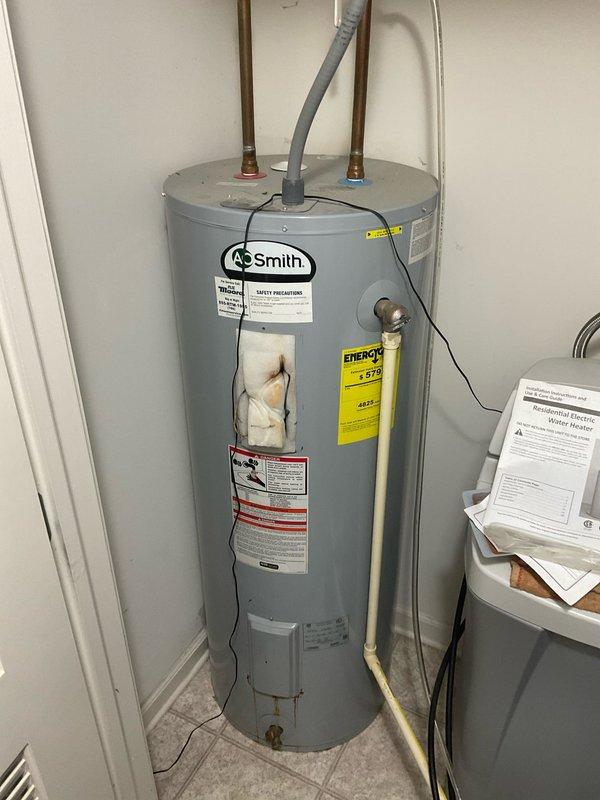 Completed estimate for water heater replacement. Documented existing A.O. Smith unit showing visible rust staining and signs of previous moisture issues, indicating need for replacement with proper assessment of current plumbing connections including copper supply lines and existing valve configuration.
