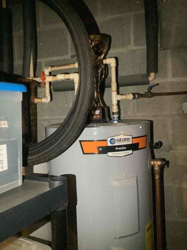 Completed basic monthly HVAC maintenance service on geothermal cooling system. During inspection, identified active water leak at connection point where geothermal system interfaces with water heater in utility room. Documented leak condition with photos showing water heater, pressure tank, and plumbing connections for follow-up repair recommendation.