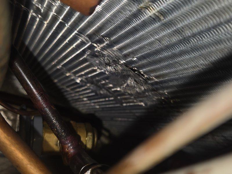 Responded to no cooling complaint on system with recently replaced TXV. Upon arrival, inspected evaporator coil and refrigerant lines. Found significant debris accumulation and contamination between coil fins, restricting airflow and reducing heat transfer efficiency. Noted oxidation on copper refrigerant lines consistent with system age. Documented coil condition with photos showing dirt buildup and discoloration throughout fin assembly. System requires thorough coil cleaning to restore proper airflow and cooling capacity.