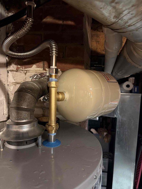 Responded to emergency call for hot water leak from recently installed temperature and pressure relief valve on A.O. Smith Signature 100 water heater. Upon arrival, found T&P relief valve had discharged, causing water intrusion into basement area. Inspected water heater installation, including copper supply piping, inlet/outlet connections, expansion tank with brass fittings and corrugated flexible connector, and T&P relief valve discharge pipe. Assessed system pressure and temperature conditions to determine cause of valve activation. Replaced faulty temperature and pressure relief valve and verified proper operation of expansion tank to prevent excessive system pressure buildup. Tested all connections for leaks, confirmed proper water flow restoration, and verified system returned to normal operating parameters with no further discharge occurring.