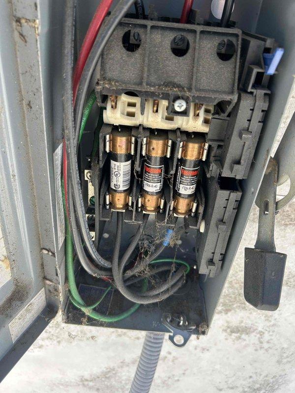 Responded to no cooling complaint and performed troubleshooting on split system air conditioning unit. Inspected exterior disconnect box and found accumulated debris, dust buildup, and aged fuse assembly with visible wear on terminals and connections. Examined indoor air handler unit with front access panel removed, revealing internal electrical components, control board, and wiring connections requiring attention to restore proper operation.