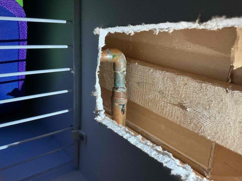 Responded to report of outdoor spigot leaking into basement. Upon inspection, located copper pipe penetration through exterior wall with significant deterioration of wall material and sealant around pipe entry point. Found evidence of water infiltration resulting in ice buildup on interior HVAC system components and surrounding surfaces, indicating active leak allowing moisture and cold air to enter conditioned space. Documented corroded copper piping with green patina, compromised wall penetration with exposed cardboard backing material, and frost accumulation on interior mechanical equipment. Identified need for pipe replacement, proper wall sealing, and restoration of weather barrier at penetration point to prevent further water damage and air infiltration.