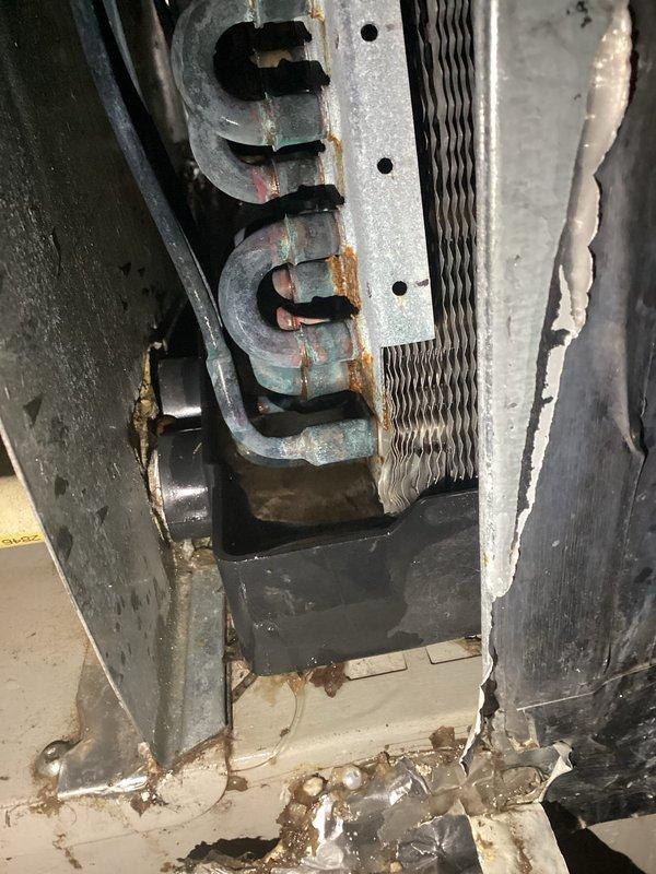Responded to no-cooling complaint on residential air conditioning system. Upon arrival, found thermostat displaying 74 degrees but system not operating. Performed diagnostic evaluation of HVAC equipment and identified failed components in aging system with visible corrosion on heat exchanger assembly and ductwork connections. Documented equipment condition showing extensive rust on metal brackets, clamps, and connection points indicating prolonged moisture exposure. Advised customer of findings and provided recommendations for necessary repairs to restore cooling operation.