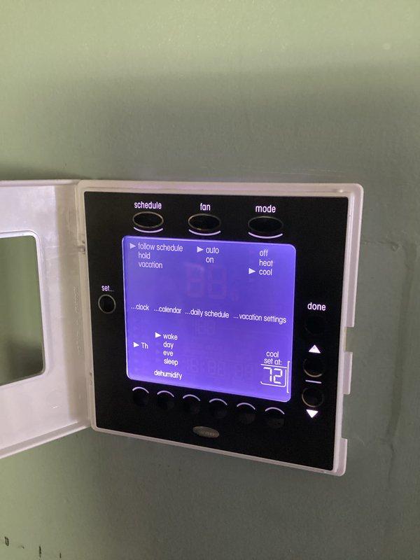 Responded to service call for non-operational air conditioning system. Upon arrival, performed diagnostic evaluation of HVAC unit and thermostat controls. Inspected programmable digital thermostat showing proper display function and verified temperature settings at 72°F with multiple schedule modes available. Examined system control board assembly containing dual-layer PCB with integrated circuits, capacitors, and wire harness connections - all components appeared in good working condition with no visible signs of failure or damage. Completed system assessment and documented equipment condition with photographic evidence of thermostat interface and control board assembly for service records.