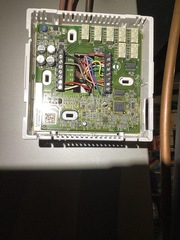 Responded to service call for non-operational air conditioning system. Upon arrival, performed diagnostic evaluation of HVAC unit and thermostat controls. Inspected programmable digital thermostat showing proper display function and verified temperature settings at 72°F with multiple schedule modes available. Examined system control board assembly containing dual-layer PCB with integrated circuits, capacitors, and wire harness connections - all components appeared in good working condition with no visible signs of failure or damage. Completed system assessment and documented equipment condition with photographic evidence of thermostat interface and control board assembly for service records.