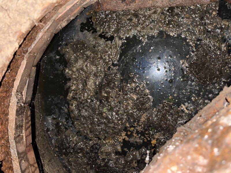 Responded to clogged main drain line. Located and accessed ground-level cleanout, which showed significant deterioration with heavy rust on metal cover and corroded rim components. Upon opening access point, found standing water with sediment and debris accumulation in the basin, indicating complete blockage in the main sewer line. Performed mechanical cable augering through the main drain to clear obstruction and restore proper flow. Removed accumulated debris and sediment from cleanout basin. Verified drainage system functionality and confirmed water flow resumed normally through the line. Recommended monitoring for recurring issues and future cleanout replacement due to advanced deterioration of access components.