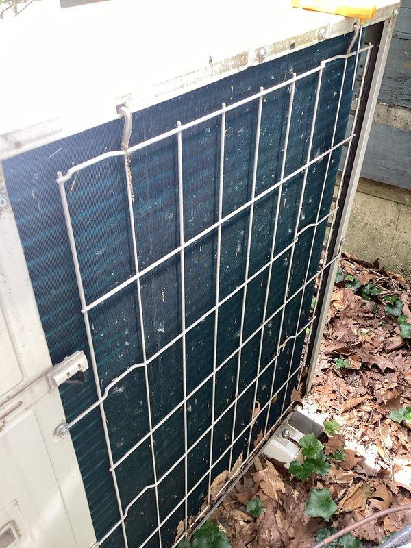 Responded to pressure error alert on residential air conditioning system. Upon arrival, found unit displaying yellow warning triangle indicating system pressure fault and non-operational status. Performed diagnostic assessment of outdoor condensing unit, which revealed heavily soiled condenser coils with significant accumulation of dirt, debris, and organic material restricting airflow. Documented ambient temperature readings and current system conditions. Condenser fins showed dark discoloration from extended exposure and lack of maintenance cleaning. Recommended thorough coil cleaning and complete system pressure testing to restore proper operation and resolve error condition.