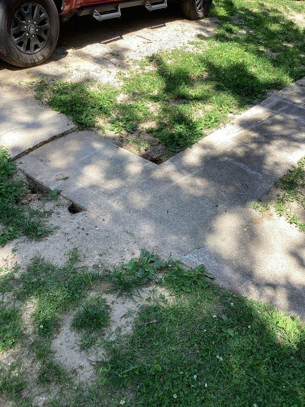 Responded to warranty callback for plumbing installation where a 2-inch stub protrusion in the concrete walkway created a trip hazard. Upon arrival, documented severely deteriorated concrete surfaces with multiple cracks, broken sections, and a protruding stub that posed safety concerns for residents with mobility challenges. Assessed the walkway damage and surrounding areas where vegetation had encroached on deteriorating concrete sections. Captured photographic documentation of the hazardous conditions including the stub protrusion, concrete deterioration, and trip hazards for warranty correction planning.