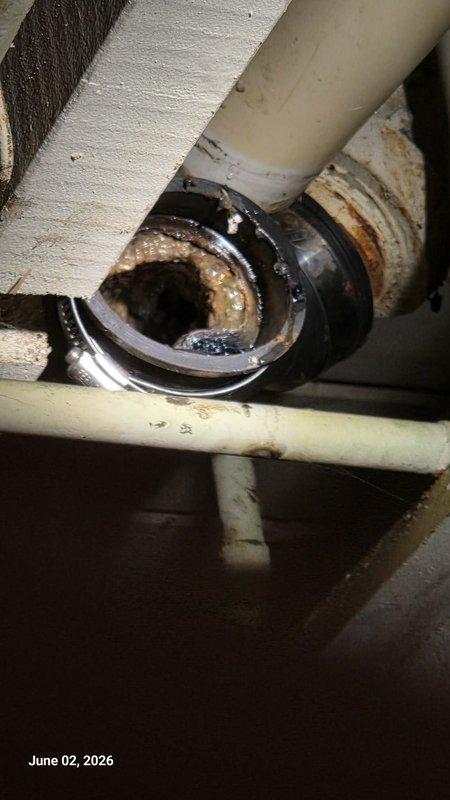 Responded to emergency water leak originating from dishwasher discharge line causing flooding on kitchen floor and water penetration through basement ceiling. Upon arrival, located source of leak at corroded dishwasher drain tailpiece and P-trap assembly showing extensive mineral buildup and deterioration. Replaced failed metallic drain fitting and corroded trap components with new PVC drain assembly. Inspected all connections for proper sealing and tested system under full flow conditions to verify leak elimination. Cleaned affected plumbing area and confirmed no additional water discharge to basement below.