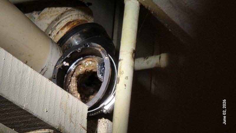 Responded to emergency water leak originating from dishwasher discharge line causing flooding on kitchen floor and water penetration through basement ceiling. Upon arrival, located source of leak at corroded dishwasher drain tailpiece and P-trap assembly showing extensive mineral buildup and deterioration. Replaced failed metallic drain fitting and corroded trap components with new PVC drain assembly. Inspected all connections for proper sealing and tested system under full flow conditions to verify leak elimination. Cleaned affected plumbing area and confirmed no additional water discharge to basement below.