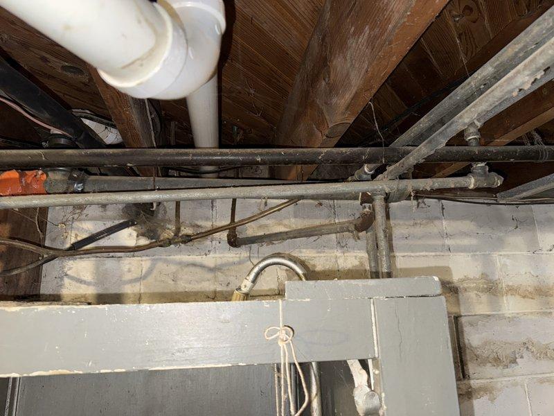 Responded to service call for reduced hot water flow while cold water pressure remained normal. Upon inspection of the crawl space plumbing system, identified corroded valve fitting on the hot water line as the source of the restriction. The galvanized piping showed significant age-related deterioration with visible rust accumulation on the affected valve component, which was impeding proper water flow. Documented the condition of the existing plumbing infrastructure, including the arrangement of supply lines, fittings, and structural mounting. Photographed the corroded valve assembly and surrounding pipe network for service records.
