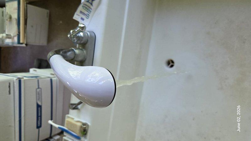 Completed monthly prepaid plumbing inspection of residential property. Inspected toilet tank assembly, noting significant mineral deposits and water staining on interior surfaces; flush valve mechanism and float valve assembly operating properly despite visible age-related buildup. Examined water heater installation, verifying proper drain valve function and connection integrity; all components functioning within normal parameters with no active leaks detected.