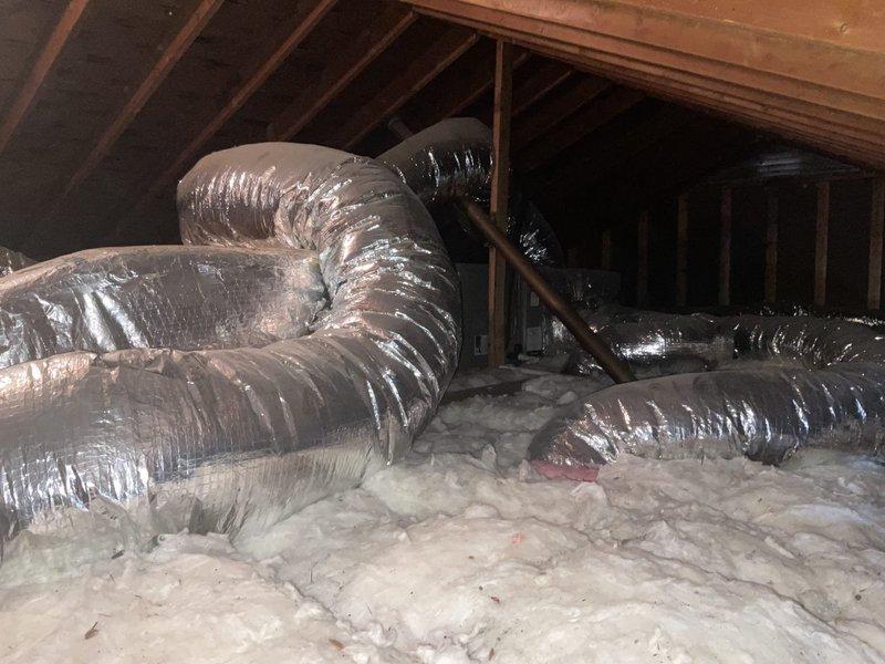 Conducted comprehensive attic inspection to assess ductwork system and provide duct cleaning estimate. Evaluated extensive flexible ductwork installation throughout attic space, including multiple runs of metallic flex ducts in both silver and dark-colored materials. Documented current condition of HVAC distribution system, noting ductwork routing, insulation coverage, and accessibility for cleaning procedures. Photographed attic space showing fiberglass insulation coverage and ductwork configuration to support estimate preparation for complete duct cleaning service.