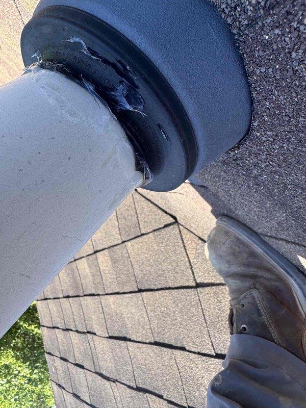 Inspected rooftop pipe penetration and documented deteriorated rubber boot flashing with visible tears, cracks, and split sections compromising weatherproof seal. Applied silicone flashing material to reinforce and seal damaged areas around PVC pipe penetration through asphalt shingle roof. Photographed existing conditions showing compromised flashing collar and completed repair work to prevent water infiltration at roof penetration point.