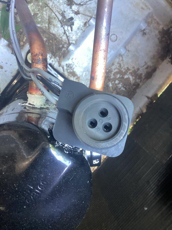 Responded to no-cooling call on 2-year-old Bryant air conditioning system. Upon arrival, accessed unit using key left under doormat as tenant was not present. Conducted visual inspection of condenser unit and identified dark burnt spot on electrical components, confirming suspected electrical failure. Documented extensive corrosion and rust staining on condenser base plate and mounting surfaces, along with oxidized copper refrigerant lines indicating moisture exposure. Photographed damaged electrical connector and motor assembly showing signs of thermal damage. System requires electrical component replacement to restore operation.