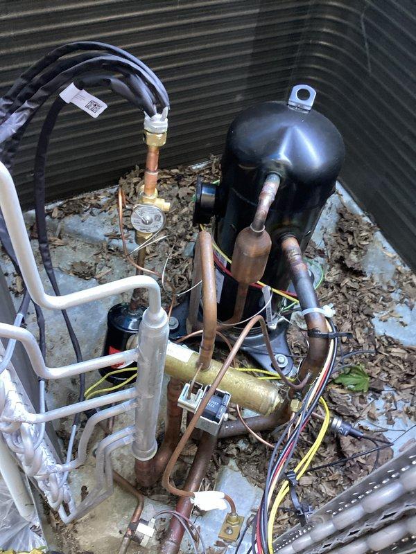 Diagnosed heat pump system with malfunctioning reversing valve affecting heating/cooling operation. System currently operational but requires return visit to replace defective reversing valve. Unit exterior shows normal debris accumulation around compressor and refrigerant lines, with thermostat displaying proper communication and temperature readings at 73 degrees.
