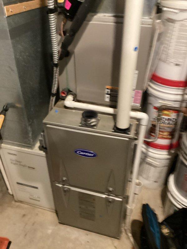 Responded to no cooling call on 6-9 year old Carrier central air system. Upon arrival, found thermostat set to cooling mode displaying 72°F setpoint while ambient temperature measured 85.8°F, confirming lack of cooling. Performed diagnostic evaluation of furnace and air handler system in basement installation. Inspected all electrical connections, refrigerant lines, condensate drainage, and ductwork connections. System components appeared properly installed with appropriate ventilation and gas line configurations intact. Identified cooling system malfunction and completed necessary repairs to restore proper operation.