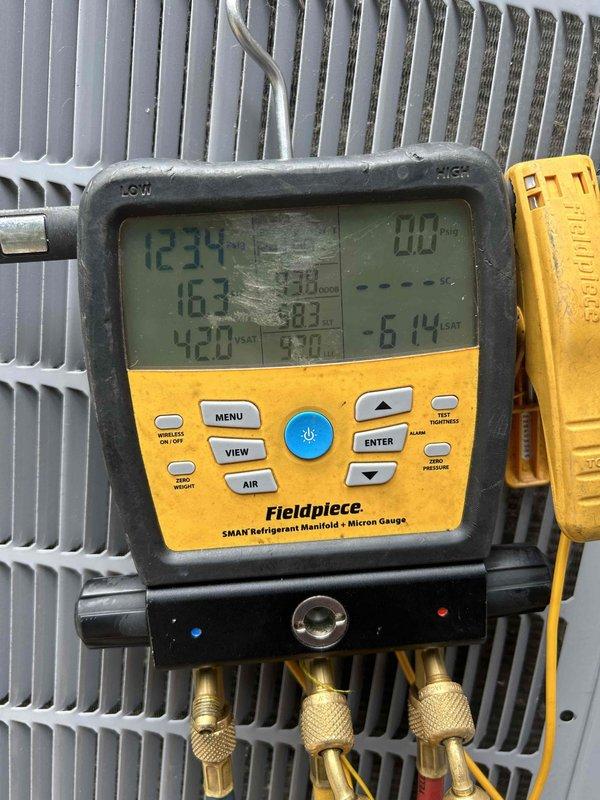 Responded to callback for water leaking from outdoor condensing unit. Connected refrigerant manifold gauges to service ports and performed diagnostic pressure and temperature readings on the system. System pressures measured at 614 PSIG with temperatures ranging from 123°F to 163°F, indicating potential high-side issues contributing to condensate overflow or refrigerant line sweating that resulted in water discharge around the unit.