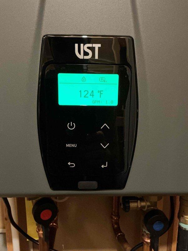 Returned to property for follow-up service on tankless water heater system after consulting with technical support. Upon arrival, performed diagnostic evaluation of UST brand tankless water heater unit. Verified system operation and monitored output temperature, which registered at 124°F with flow rate of 1.3 gallons per minute on digital display panel. Inspected copper supply line connections, inlet/outlet valves, and associated plumbing connections for proper installation and function. Adjusted system settings as needed per manufacturer specifications and technical support recommendations. All components operating within normal parameters at time of service completion.