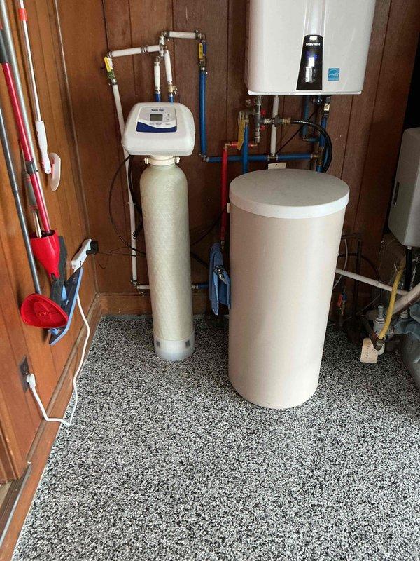 Completed re-installation of North Star water softener system in residential utility room. Properly configured all supply lines, drain connections, and brine system using color-coded PVC and copper piping with appropriate fittings and valves. Verified digital control head functionality displaying correct operational parameters, established proper electrical connection, and ensured integration with existing tankless water heater system. All plumbing connections tested and confirmed leak-free with system operational.