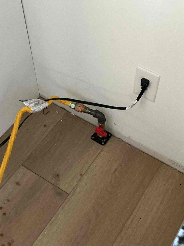 Responded to gas odor complaint and coordinated with gas utility provider for leak detection. Gas company confirmed leak location above the shut-off valve requiring repair. Documented existing conditions including gas range with active burner operation and gas line configuration with shut-off valve and flexible connector at point of service.