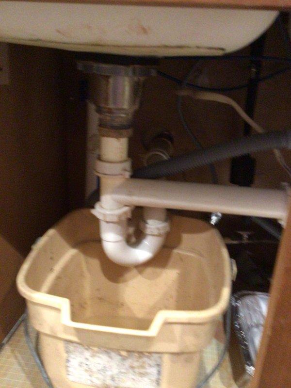 Responded to kitchen sink drainage issue with suspected clog beyond the trap and garbage disposal problems. Inspected under-sink plumbing assembly including P-trap configuration and drain lines, assessed double-basin stainless steel sink with pull-down spray faucet, and evaluated drainage performance. Addressed blockage in drainage system to restore proper water flow and functionality to kitchen sink and disposal unit.