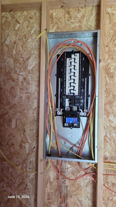 Completed electrical rough-in installation for residential construction project, including running Romex wiring horizontally across wall studs, securing cables with proper fasteners, and installing blue electrical boxes at designated outlet and switch locations. Mounted and wired main electrical panel with dual-row circuit breaker configuration, organized incoming branch circuits with proper color-coded cabling (orange, yellow, red, and white conductors), and installed digital metering device at panel base per code requirements.