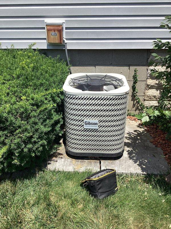 Responded to air conditioning repair request at residential property. Performed diagnostic inspection of complete HVAC system including Gibson brand outdoor condensing unit and indoor furnace assembly. Inspected outdoor condenser unit positioned on concrete pad, verified proper clearances from landscaping and structure, examined diamond-pattern protective grille for damage, and assessed overall unit condition. Checked indoor furnace installation in basement utility area, inspected gas line connections with shutoff valve, examined PVC condensate drain and vent piping, and evaluated flexible aluminum ductwork with fiberglass insulation. Noted heavily soiled air filter requiring replacement due to excessive dust accumulation affecting system airflow and efficiency. Verified all electrical connections, reviewed manufacturer specification labels, and documented equipment configuration. System operational upon completion of service call.