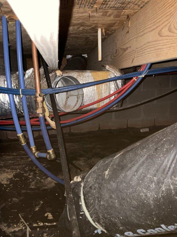 Conducted inspection of crawl space ducting and mechanical systems. Documented existing conditions including insulated ductwork with visible aging and dust accumulation, PEX plumbing lines with brass fittings, hydronic system components, and mechanical equipment installation beneath floor joists.