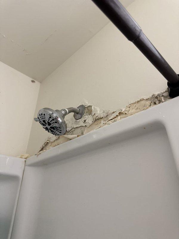 Responded to service call for constantly dripping showerhead in residential bathroom. Upon arrival, inspected chrome-finished showerhead assembly and shower valve system. Identified worn internal washer and deteriorated O-ring seals within the shower valve mechanism causing persistent drip. Disassembled showerhead from wall-mounted arm fitting and inspected for mineral buildup and component wear. Replaced faulty washers and seals, cleaned aerator screen, and reassembled unit. Tested water flow and verified complete elimination of drip. Inspected surrounding shower area and noted pre-existing wall damage near ceiling line unrelated to plumbing issue. All fixtures restored to proper working order with no leaks detected.