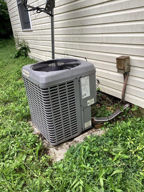 Performed standard air conditioning cleaning and check service on residential outdoor condenser unit. Inspected system components, cleaned condenser coils, verified electrical connections at disconnect box, and confirmed proper unit operation. Noted vegetation growth around unit base requiring customer attention to maintain adequate airflow clearance.