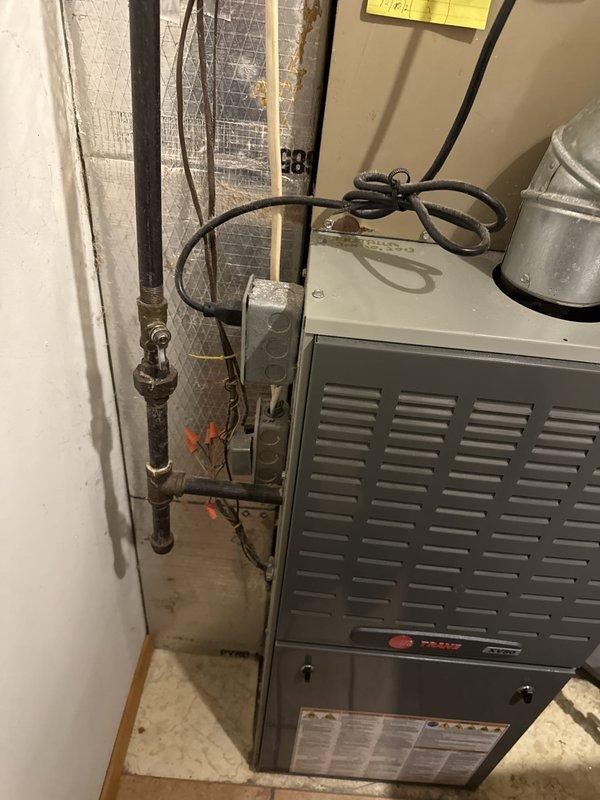 Responded to gas leak call at water heater location. Conducted thorough visual inspection of gas piping system, identifying aged copper and brass connections with visible corrosion and patina near water heater installation. Performed pressure test on gas lines to locate source of leak. Inspected gas valve, pipe joints, and connections at water heater and adjacent furnace system. Documented existing conditions showing deteriorated piping with significant oxidation requiring attention. Captured photographic evidence of corroded gas line components and overall system configuration for repair recommendations.