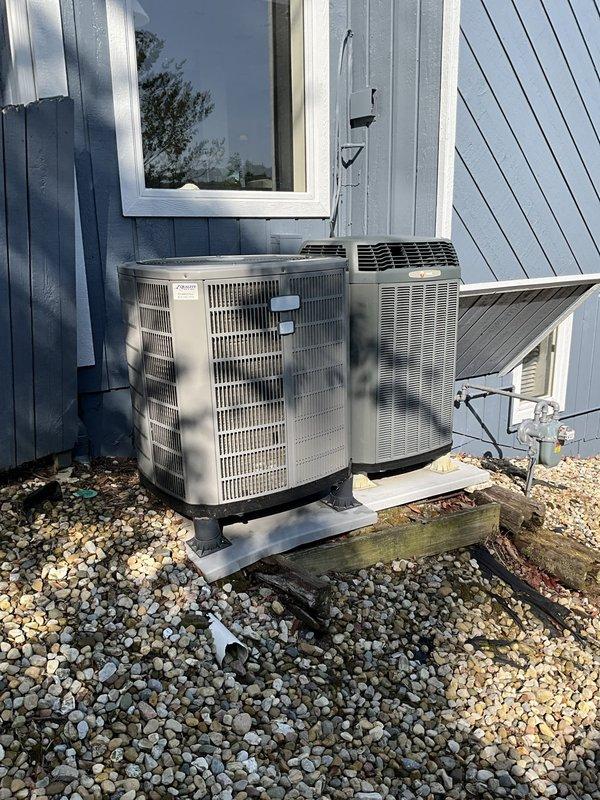 Conducted cooling system assessment for residential property with inadequate cooling capacity. Evaluated existing dual outdoor condensing unit configuration, including Bryant cylindrical unit and secondary beige condensing unit, both mounted on concrete pads with proper drainage base. Documented current equipment specifications, refrigerant line routing, electrical conduit installations, and mounting configurations to determine replacement requirements for improved cooling performance.
